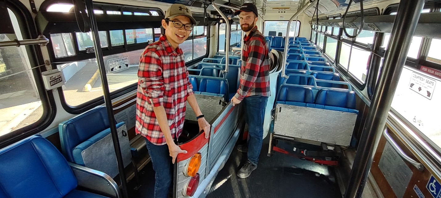 Two men standing in a bus

Description automatically generated