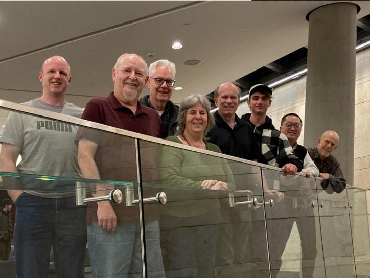 A group of people standing on a glass railing

Description automatically generated
