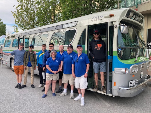 A group of people standing in front of a bus Description automatically generated