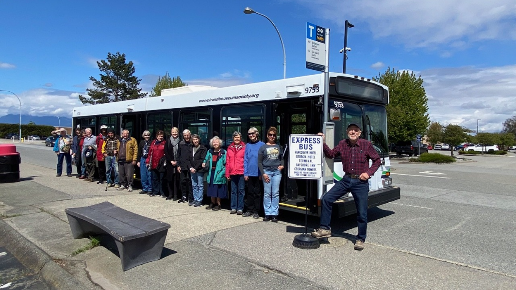 A group of people standing in a line next to a bus Description automatically generated